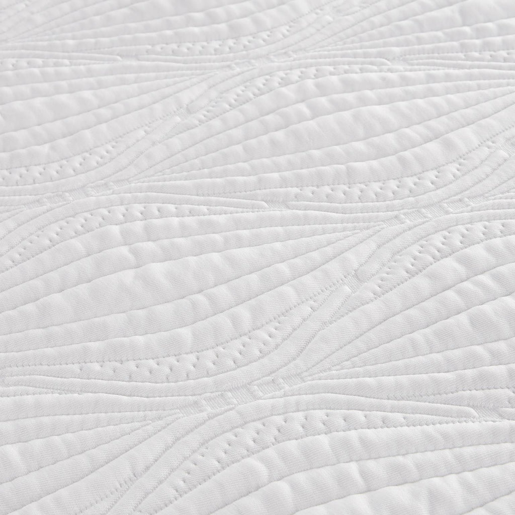 Close-up of a white quilted fabric with a leaf-like stitched pattern.