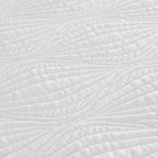Close-up of a white quilted fabric with a leaf-like stitched pattern.