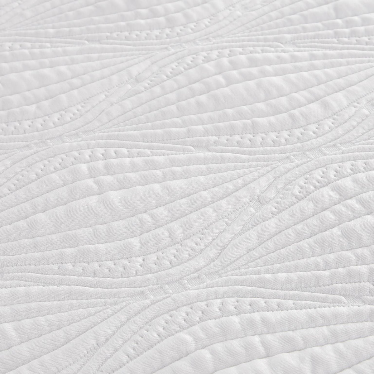 Close-up of a white quilted fabric with a leaf-like stitched pattern.