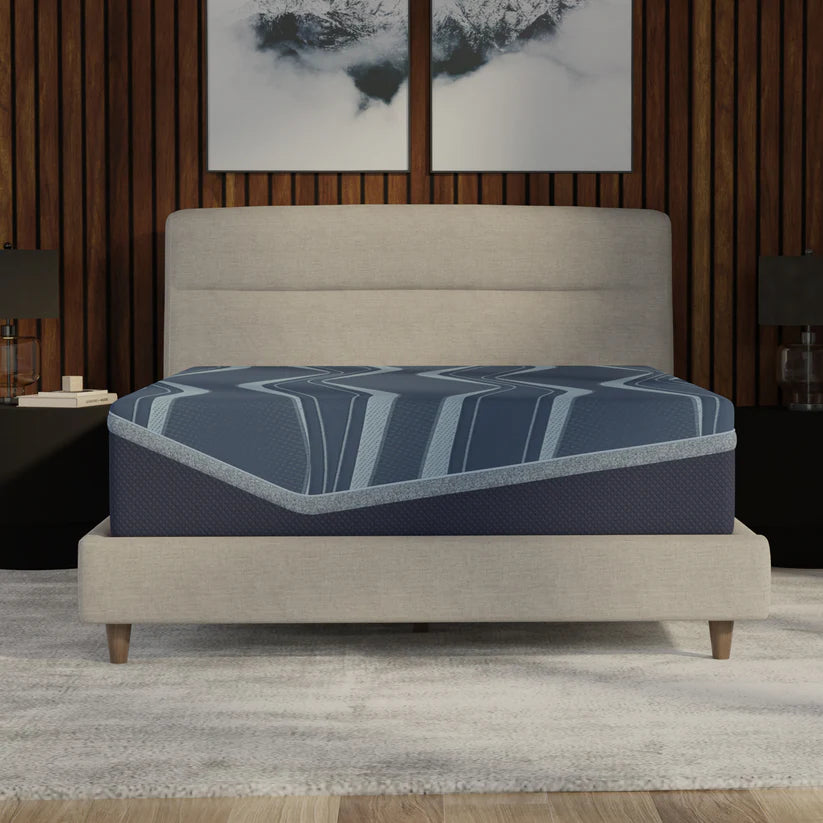 Blue mattress on a beige bed frame in a bedroom setting with abstract art on the wall.