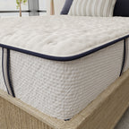 Close-up of a mattress with a quilted surface and blue trim on a wooden bed frame.