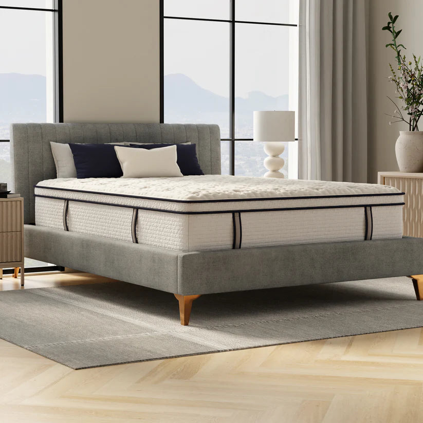Gray upholstered bed with a mattress in a modern bedroom setting.