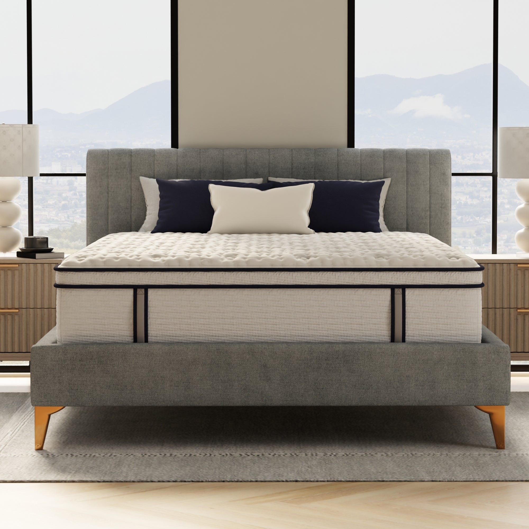 Gray upholstered bed with a mattress in a room with large windows.