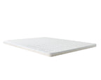 A white mattress topper with a quilted geometric pattern on top and a textured edge, shown floating at an angle against a solid white background.