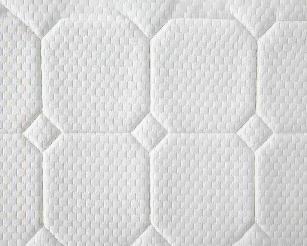 Close-up of a white quilted mattress or cushion surface with stitched octagonal and diamond panels and a textured fabric pattern.