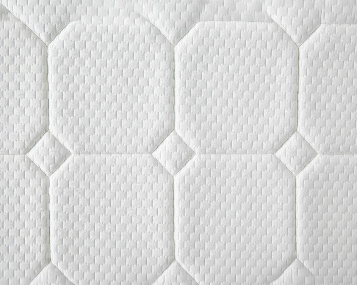Close-up of a white quilted mattress or cushion surface with stitched octagonal and diamond panels and a textured fabric pattern.