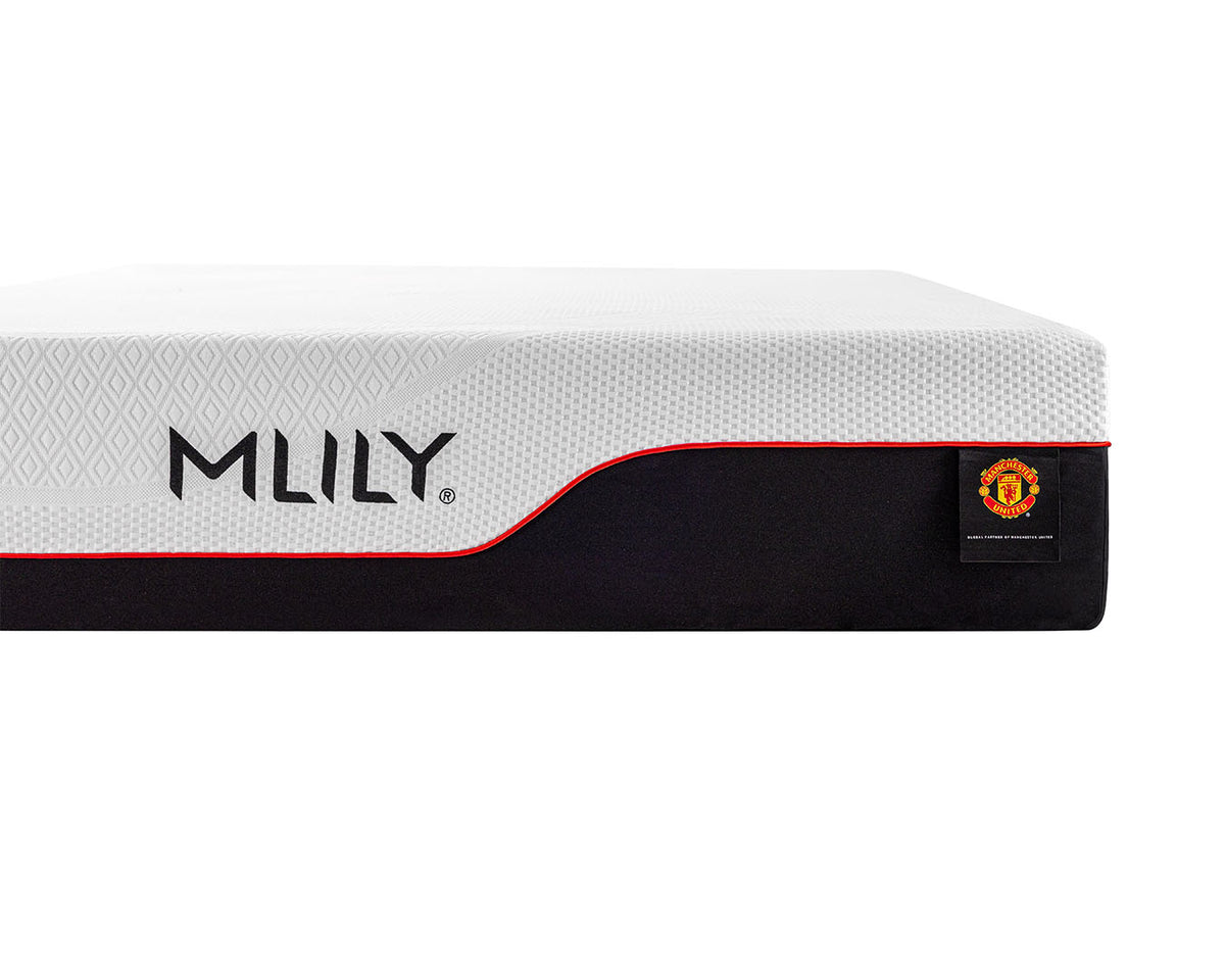 A close-up of an MLILY mattress showing its white textured top surface, a black side panel with the MLILY logo, and a small Manchester United crest patch.