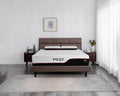 A modern bed frame with a brown upholstered headboard and footboard, styled in a minimalist bedroom setting. The mattress is covered with a white mattress topper featuring the brand name 'MILY.