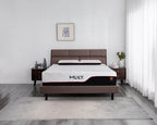A modern bed frame with a brown upholstered headboard and footboard, styled in a minimalist bedroom setting. The mattress is covered with a white mattress topper featuring the brand name 'MILY.